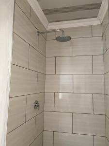 bagno con doccia e piastrelle bianche di Cozy corner a East London