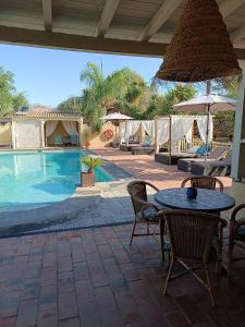 a patio with a table and chairs next to a pool at Quinta Pereiro Tropic Garden, Algarve in Moncarapacho