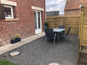 a patio with a table and chairs next to a brick building at Maison de campagne in Hamelet
