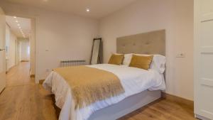 una camera da letto con un grande letto con lenzuola bianche e cuscini dorati di La Paloma VUT 7109 AS a Luanco