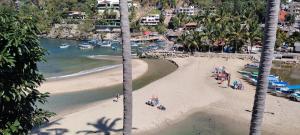 a beach with a group of people and boats in the water at Villas del Amor Amor in Puerto Vallarta