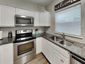 a kitchen with white cabinets and a stove and a sink at Forever in Flip Flops in Port Aransas