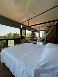 a bedroom with a white bed and a large window at Centro Sati Bungalow in Cuatunalco