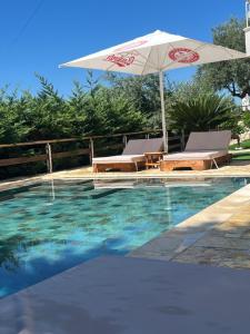 a swimming pool with an umbrella and two chairs and a table at Dhermi Villa 1 in Kondaq