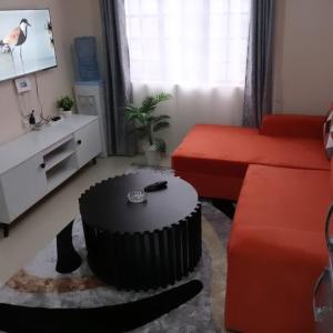 a living room with a red couch and a table at Maggies suites and Bnb in Nairobi +2 photos