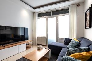ein Wohnzimmer mit einem blauen Sofa und einem Fernseher in der Unterkunft Maison spacieuse 3 chambres - 35 min Paris centre in Romainville