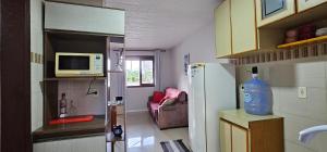 Una pequeña cocina con nevera y microondas. en Residencial Hannah - Casa 6 - Porto Belo SC - Bairro Perequê, en Porto Belo