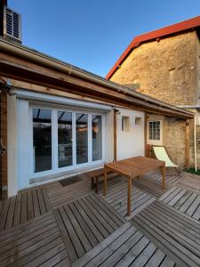 a wooden deck with a table and a bench at Maison 4p, parking, terrasse, jardin in Chancenay