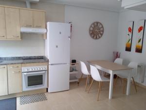 a kitchen with a white refrigerator and a table at Apartamento L' Espumeru in Posada de Llanes +27 photos