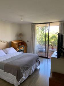 Un dormitorio con una cama y un televisor y un balcón. en Habitación Metro Escuela Militar, en Santiago