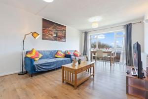 a living room with a blue couch and a table at Luxury 2 Bedroom Apartment with Free Parking Opposite Queen Elizabeth Hospital in Birmingham