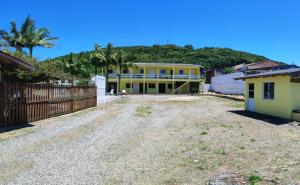 an empty driveway in front of a yellow house at Bangalô Belezas de Laguna in Laguna +5 photos