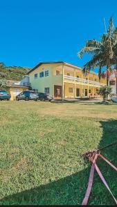 a building with a pink ribbon in front of a field at Bangalô Belezas de Laguna in Laguna