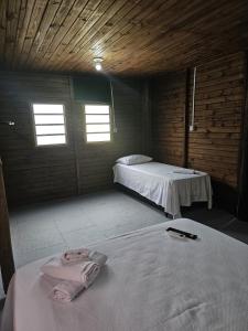 a room with two beds and two windows at Bangalô Belezas de Laguna in Laguna