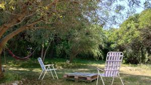 twee stoelen en een picknicktafel voor een boom bij Sol de la cumbre in La Cumbre