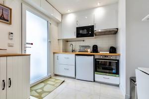 una cucina con mobili bianchi e un forno a microonde di Jolie Maison 3 à 6 pers - 35 min de Paris centre a Romainville