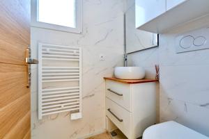 un bagno bianco con lavandino e WC di Jolie Maison 3 à 6 pers - 35 min de Paris centre a Romainville