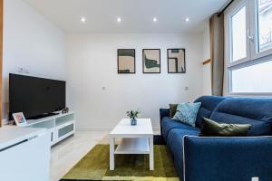 un soggiorno con un divano blu e una TV di Jolie Maison 3 à 6 pers - 35 min de Paris centre a Romainville