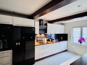 a kitchen with white cabinets and a black refrigerator at Dom na Styku in Jaworzynka