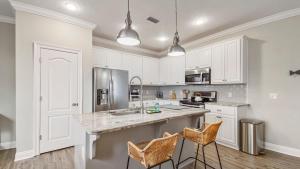 una cucina con armadi bianchi e una grande isola con sgabelli da bar di Guilty Treasure a Panama City Beach