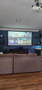 a living room with a couch and a large screen tv at Casa Próximo ao Centro Agradável e Inteligente in Poços de Caldas