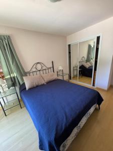 Un dormitorio con una cama azul y un espejo. en La Divina Chapadmalal, en Chapadmalal