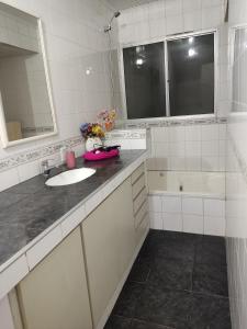 a white bathroom with a sink and a tub at Suite con entrada independiente 1 dormitorio 1 sala de estar in Rivera +14 photos