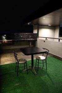 a table and two chairs on a green floor at Hotel 1140 in Linares