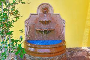 a rusty water fountain in front of a yellow wall at Loft romántico y acogedor junto al bosque in Huasca de Ocampo