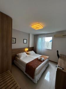 a bedroom with a large bed and a window at Apartamentos no Verano Stay in Rio de Janeiro