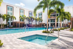 a swimming pool with palm trees in front of a building at Kompose Boutique Resort @ Theme Parks in Kissimmee