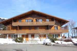 a large wooden house with a balcony in the snow at Chalet Mittaghorn in Adelboden