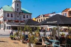 a group of people sitting at tables in a street with umbrellas at Klimatyczna kawalerka na Rynku in Gliwice