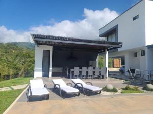 a patio with white chairs and a building at Hermosa Casa de Lujo en LAGO CALIMA in Darién