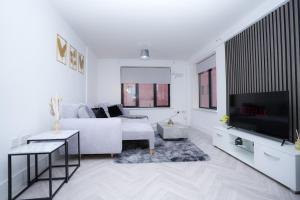 a white living room with a white couch and a tv at 2 Bed Apartment - Bham City Centre, Next to Utility Arena - Free Parking! in Birmingham