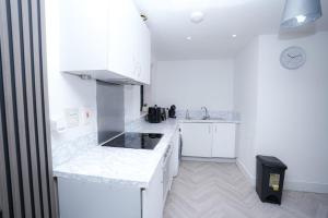 a white kitchen with white cabinets and a sink at 2 Bed Apartment - Bham City Centre, Next to Utility Arena - Free Parking! in Birmingham