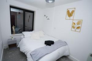 a white bedroom with a white bed with a black bag on it at 2 Bed Apartment - Bham City Centre, Next to Utility Arena - Free Parking! in Birmingham +7 photos