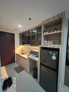 a kitchen with a black refrigerator and a sink at Masterstadt Batam Pollux Habibie A3 by Ocha in Bagam