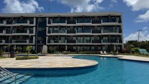 a building with a swimming pool in front of a building at Studio Confortável em Muro Alto in Ipojuca