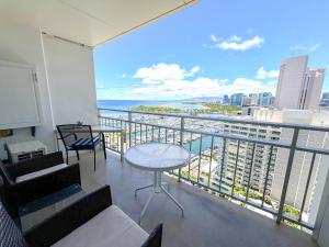 a balcony with a table and chairs and a view of the ocean at Ilikai Apt 2127 - Spacious Studio with Spectacular Ocean & Harbor Views in Honolulu