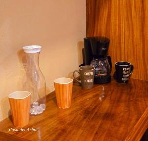 a wooden table with cups and a vase on it at Casa del Arbol in San Blas