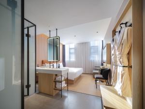 ein Hotelzimmer mit einem Bett, einem Waschbecken und einem Spiegel in der Unterkunft 桔作酒店（郑州经开中原福塔东地铁站店） in Zhengzhou