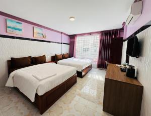 a hotel room with two beds and a flat screen tv at The Cozy Corner-Budget Hotel in Phumĭ Kâmpóng Kândal