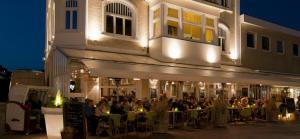 um grupo de pessoas sentadas em mesas fora de um edifício em Café Orth em Westerland