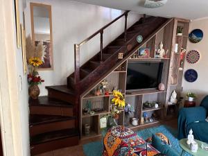 a living room with a wooden staircase with a tv at Casa Isis in Constitución +5 photos