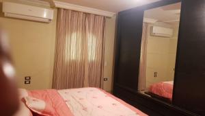 1 dormitorio con espejo grande y cama en موقع متميز, en Al Ma‘şarah al Maḩaţţah