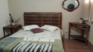 een slaapkamer met een bed met 2 kussens en een spiegel bij apto wiljan in Petrópolis