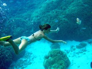 Uma mulher de biquíni a nadar no oceano. em Robinson's Cove Villas - Deluxe Wallis Villa em Papetoai
