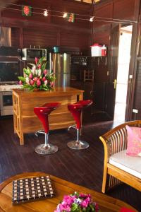a kitchen with red chairs and a table with a counter at Robinson's Cove Villas - Deluxe Wallis Villa in Papetoai