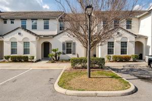 ein weißes Haus mit einem Baum in der Mitte einer Straße in der Unterkunft Universal 3BR Townhome with Pool in Davenport